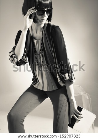 attractive fashionable girl in sunglasses with purse sitting cube in studio portrait in black and white