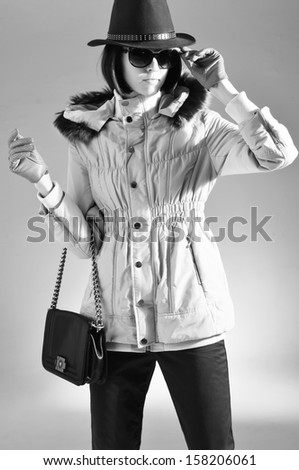 Young fashion woman in white coat with bag, sunglasses studio shot , black and white photo