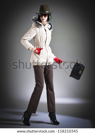 Full body Shot of an attractive fashionable girl in jacket with sunglasses, bag posing light background