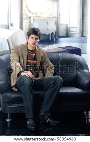 handsome young male model at interior seated on the couch