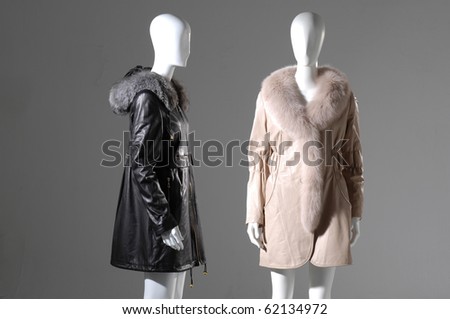 Two dummies dressed in fur coat and standing on gray background