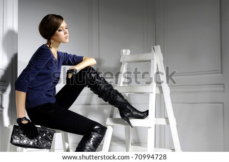 High fashion model sitting cube posing wooden ladder in the studio