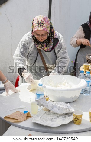 BUCHAREST, ROMANIA - MAY 17: Turkish woman cook prepares the dough for traditional suberek pie during the celebratory event Turkish Festival on May 17, 2013 in Bucharest, Romania.