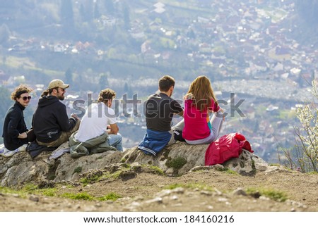 BRASOV, ROMANIA - MARCH 23: Group of unidentified hikers sit on top of Tampa Mountain and enjoy the city panorama on March 23, 2014 in Brasov, the largest city in a mountain resorts area in Romania.