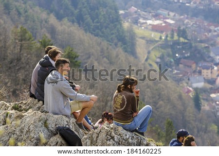 BRASOV, ROMANIA - MARCH 23: Group of unidentified young people sit on top of Tampa Mountain and enjoy city panorama on March 23, 2014 in Brasov, the largest city in a mountain resorts area in Romania.