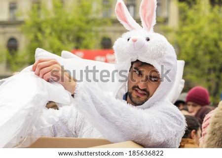 BUCHAREST, ROMANIA - APRIL 5: Unidentified man in white bunny costume give white pillows to the crowd on International Pillow Fight Day on April 5, 2014 in University Square, Bucharest, Romania.