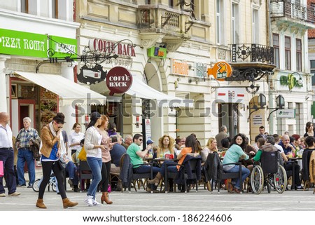BRASOV, ROMANIA - MARCH 23: Unidentified locals and tourists enjoy outdoor dining at a sidewalk cafe on March 23, 2014 in Council Square in Brasov, 7th largest and the most visited city in Romania.