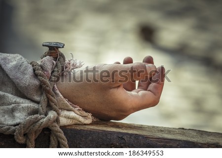 Closeup of nailed hand on wooden cross as a reenactment of the crucifixion of Jesus Christ.
