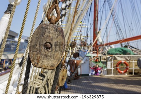 Closeup of aged vintage marine ropes and wooden tackle block on the deck of an old sailing vessel.