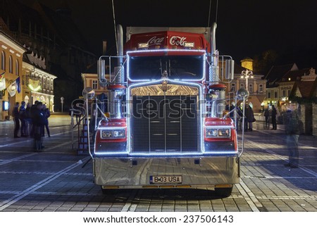 BRASOV, ROMANIA - DECEMBER 11, 2014: A Red Christmas decorated Coca-Cola truck visits Brasov city in the Council Square at night.