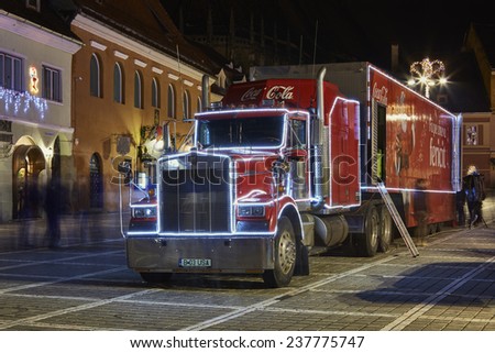 BRASOV, ROMANIA - DECEMBER 11, 2014: A Red Christmas decorated Coca-Cola truck visits Brasov city in the Council Square at night.