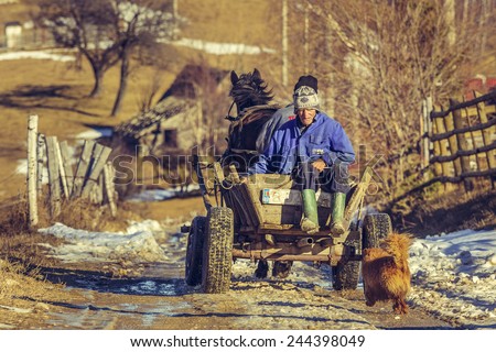 PESTERA, ROMANIA - DECEMBER 24, 2014: Unidentified highland farmers return home from laboring on the land, using a wooden horse cart, a traditional transportation vehicle still used in countryside.