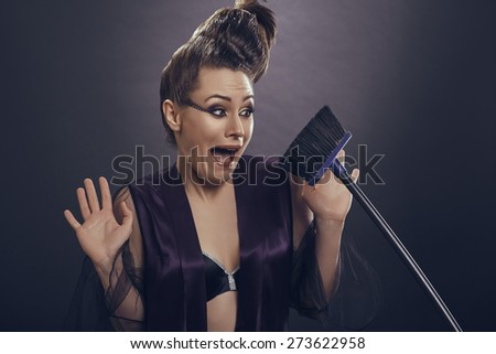Screaming stylish fashion female model in lingerie scared of holding a broom or refusing to do housekeeping tasks. I am a fashion model, not a housewife!