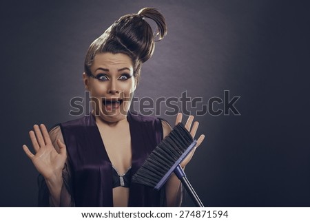 Screaming frightened fashion female model in lingerie scared of holding a broom or rejecting house cleaning tasks.