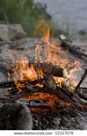 Photo of a campfire on the rocky shore of the lake