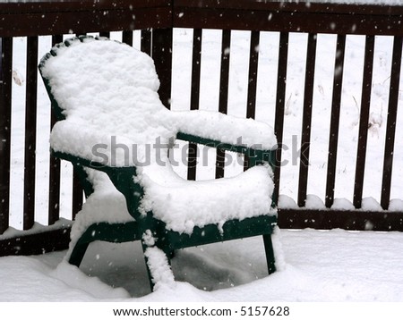 photo of snow on patio chair on a outside deck in the winter during a snow storm