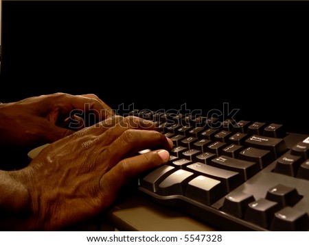 close up photo of african american hands typing on a computer keyboard while working at a computer desk. includes copy and/or cropping space for various layouts