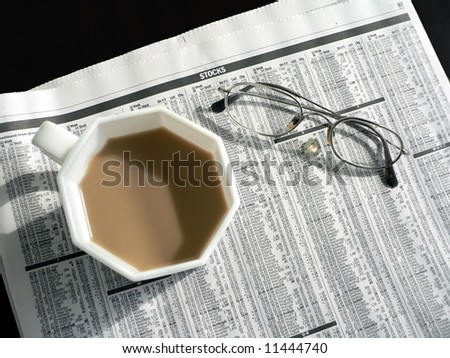 newspaper featuring the stock page with coffee and pair 0f eyeglasses