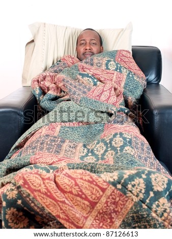 A african american man bundled under a blanket while sick. copy and cropping space included.