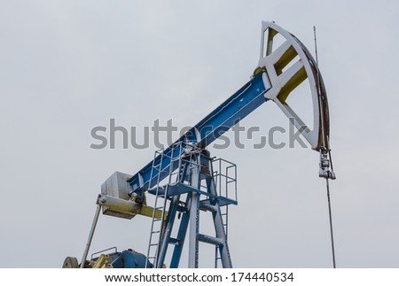 Operating oil and gas well detail profiled on white and grey sky