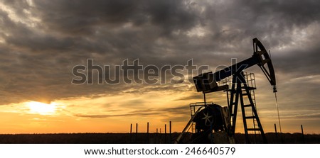 Industrial oil and gas well pump at sunset