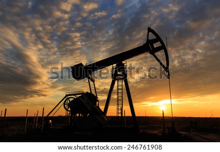 Scenery with oil and gas well pump and dramatic sunset, soft focus