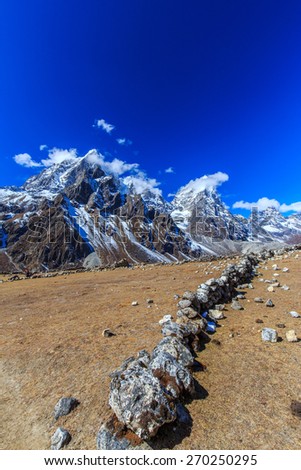 Snow covered mountains, rocky peaks and stone lodge in Himalaya