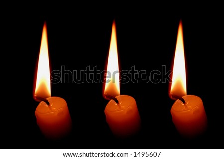 Three candles glowing in the dark
