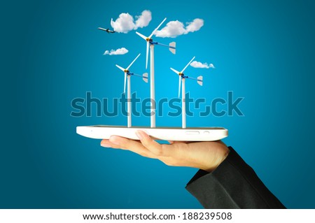 female hand holding a tablet touch computer gadget present wind turbine power generator