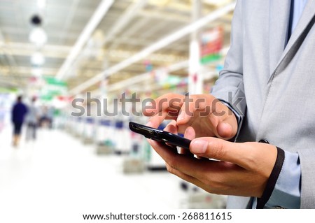 Business Man using mobile phone while shopping in supermarket.