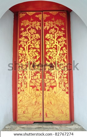 Traditional Thai art of painting on the red wooden door of Thai temple in Royal palace.