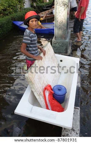 BANGKOK - OCTOBER 30: Unidentified girl with her white basin and foam sheet which will be used as boat during Thai flood crisis on October 30, 2011, Bangkok, Thailand.