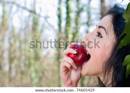 beautiful dark-haired girl eating apple in the park