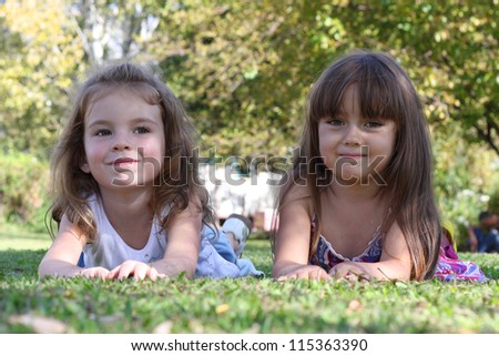 Children girl friends lying on the grass on a hot day after playing in the fresh air