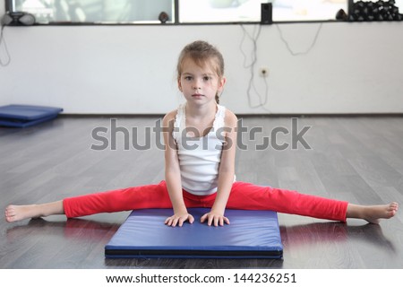The girl is engaged in sports and yoga sitting on the splits