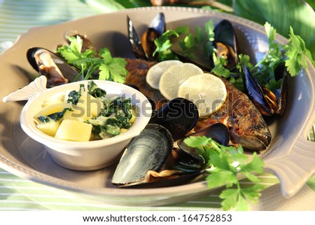 Grilled fish with herbs and lemon, top view. Mediterranean luxurious seafood concept. Fish and mussels on the grill.