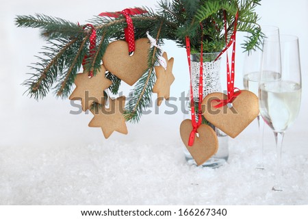 Tree dressed gingerbread ornaments. Christmas toys made ??with their own hands. Cookies on fir branches. Gingerbread, spruce, champagne glasses and snow on a white background