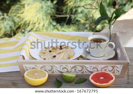 Tasty Diet oatmeal with dried fruit and raisins. Oatmeal on a tray with tea and citrus. Foodstyle.