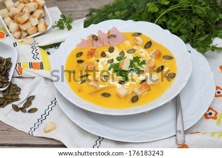 Pumpkin soup. Puree soup. Food style. Pumpkin soup puree with seeds, bacon and croutons on wooden table with parsley.
