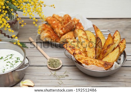 French fries potato wedges in recycled kraft paper bag on wooden old background. Fast food. Closeup.