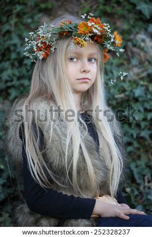 Beautiful girl with long hair and floral wreath. The child in the spring garden.
