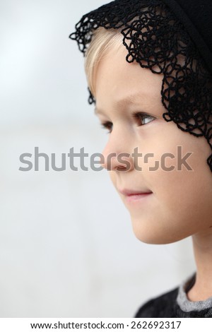 Close-up portrait in profile of adorable smiling child girl. Girl on a religious holiday with his head covered. A child with a kerchief on her head.