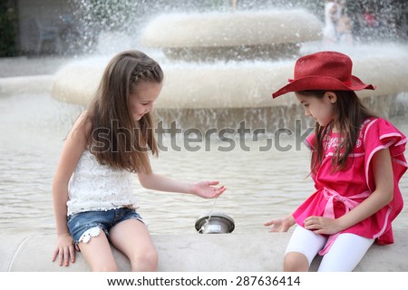Beautiful children happily playing near the fountain with water. Girlfriends near the fountain. Girls.