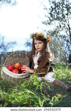 Girl with floral wreath on her head in the fall after harvest of apples. Shopping with vitamins a child.