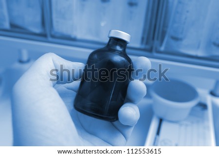 dark glass bottle in hand laboratory worker. Monochrome photo.
