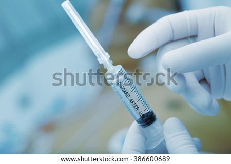 Medical syringe in the doctor\'s hands on the patient\'s background.