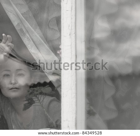 soft black and white portrait of Asian woman behind the window glass
