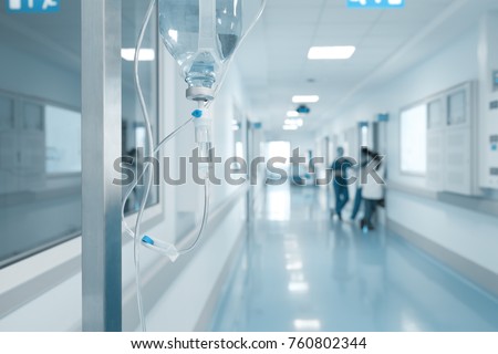 Intravenous drip on the rack on the background of talking nurses in the hospital corridor.