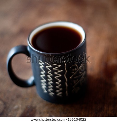 Cup of coffee on wooden table. Very shallow depth of field