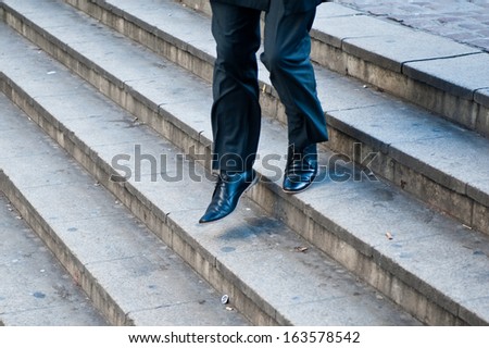 Businessman running down city stairs